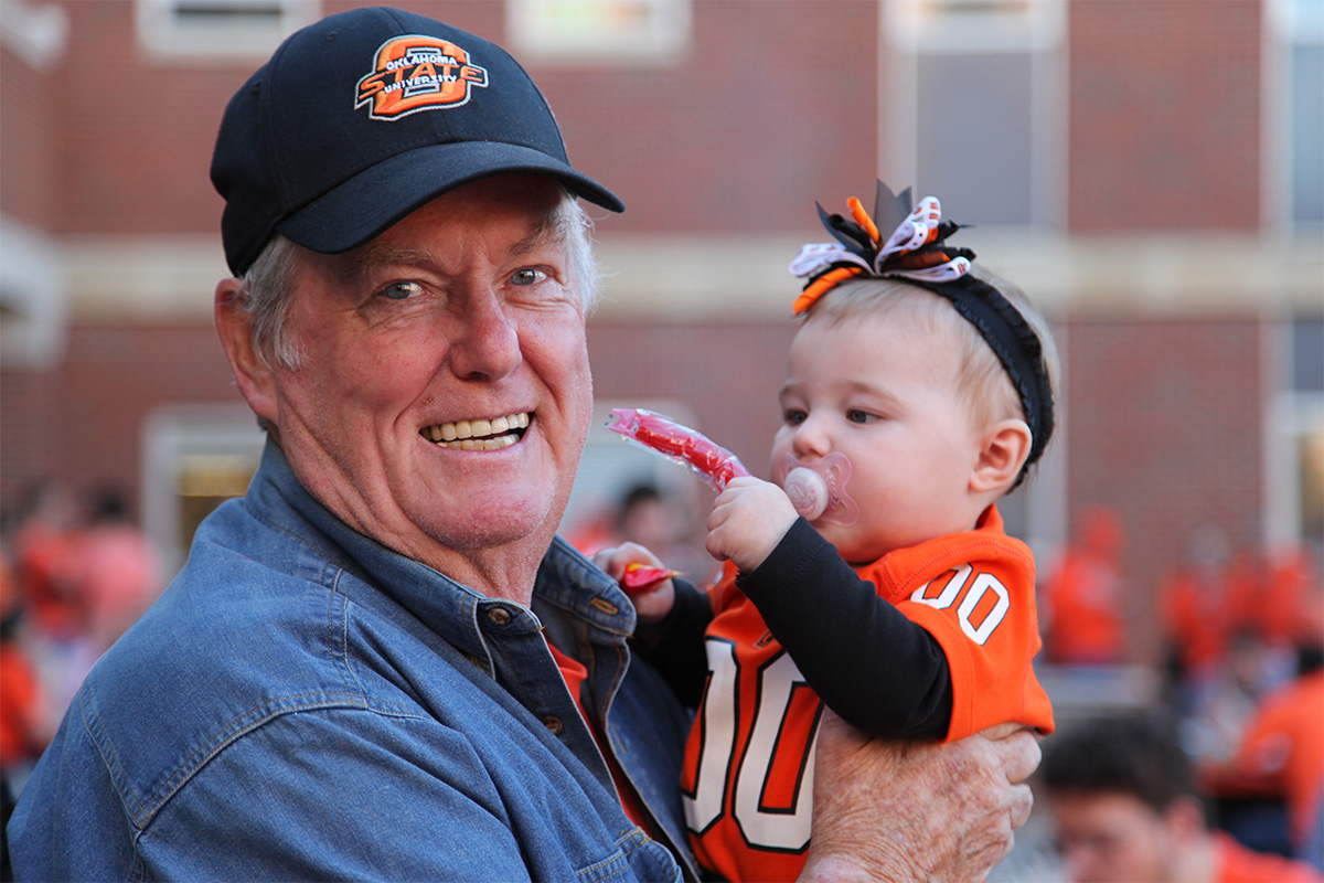 Dr. Mike Branson holding child at a the OSU Homecoming and CEAT Tailgate