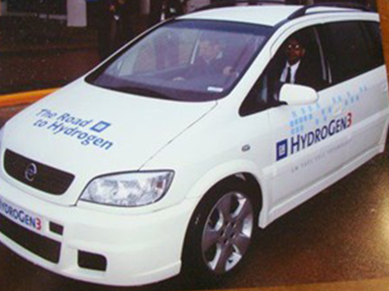 A man sitting inside a small white car.