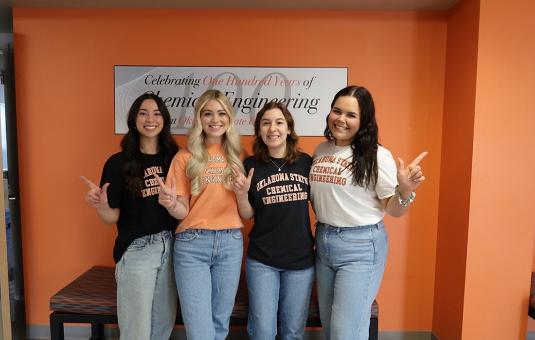 Four Oklahoma State University students give the Go Pokes sign for a portrait photo.