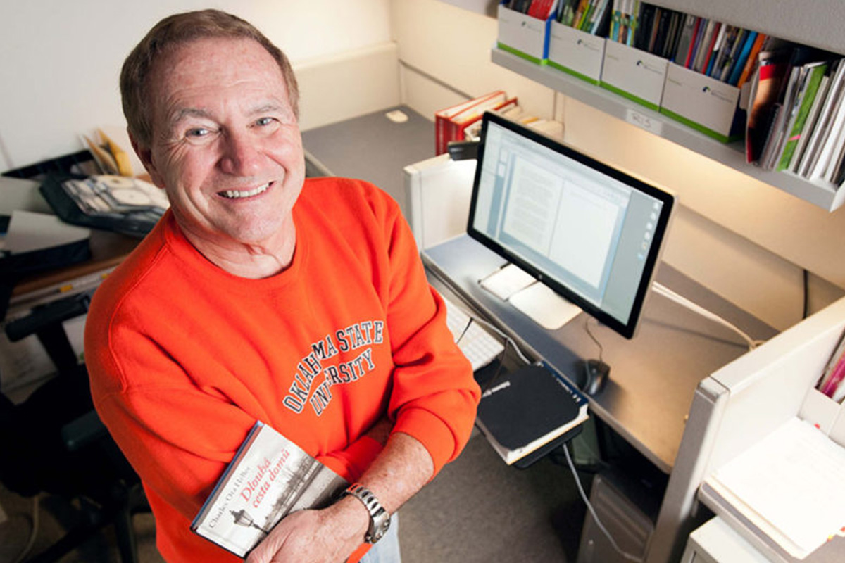 A man in an orange Oklahoma State University sweater smiles up at the camera.