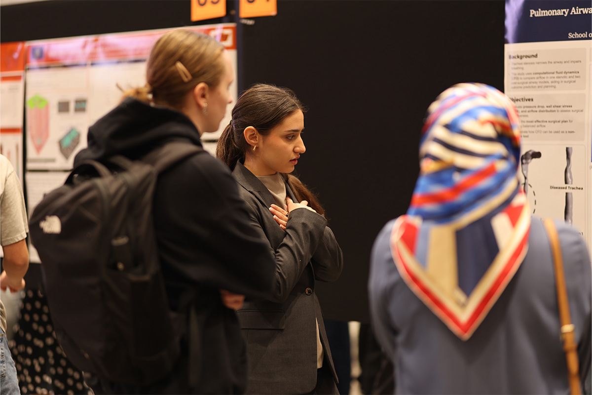 A college students discusses her research with symposium attendees.