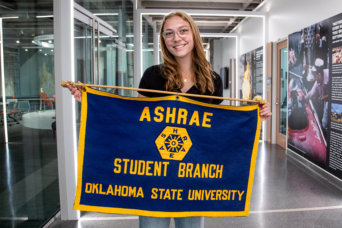 Sophie Hawkins holding ASHRAE banner in the hall of Engineering South