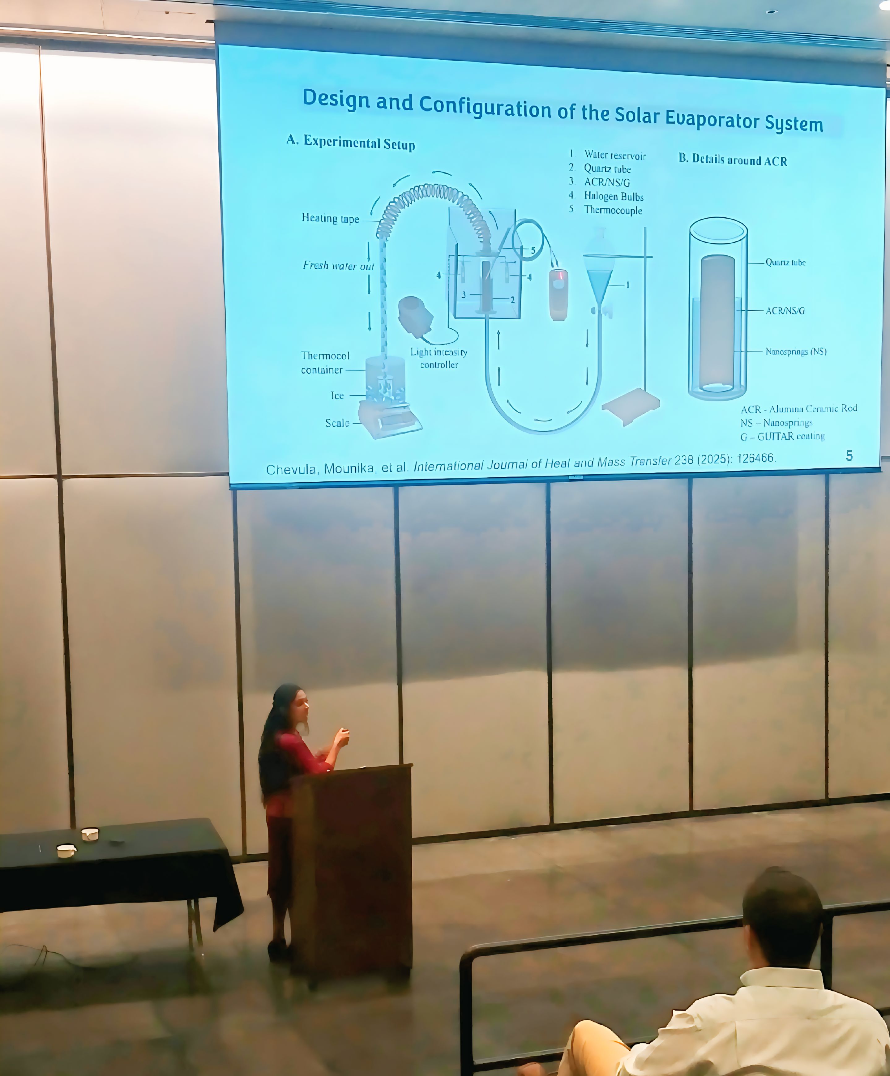 female student presenting in a lecture hall. standing at a podium and pointing to an overhead projector screen