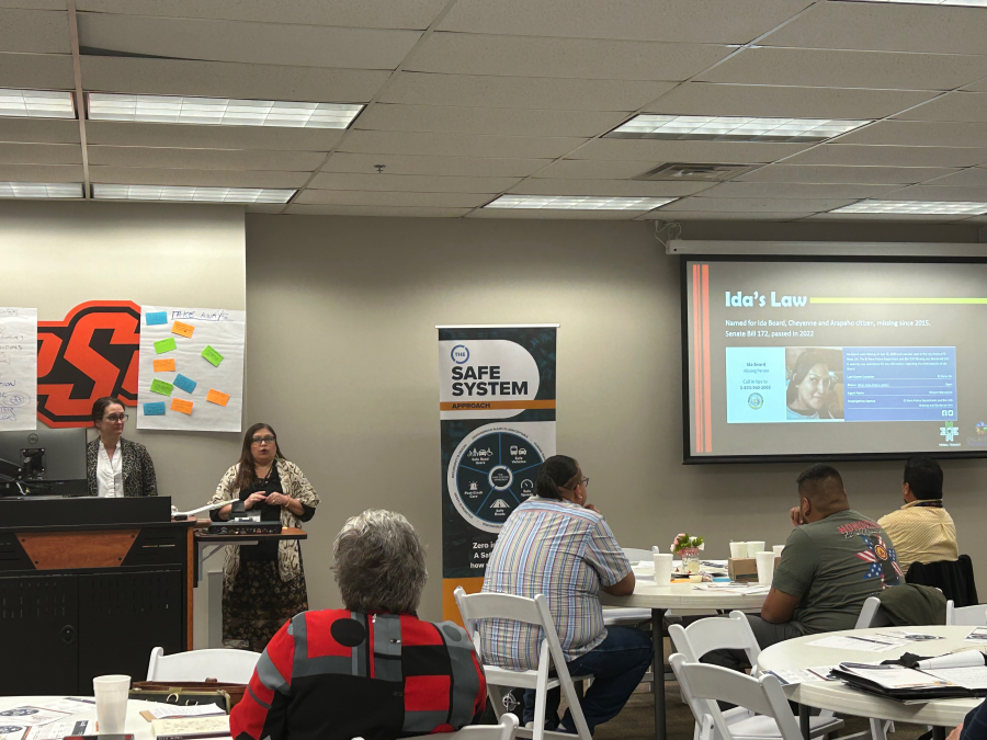 Speakers at the podium at the Safe Systems Approach for All workshop with activity poster and presentation in the background and with participants in the foreground Speakers at the podium at the Safe Systems Approach for All workshop with activity poster and presentation in the background and with participants in the foreground