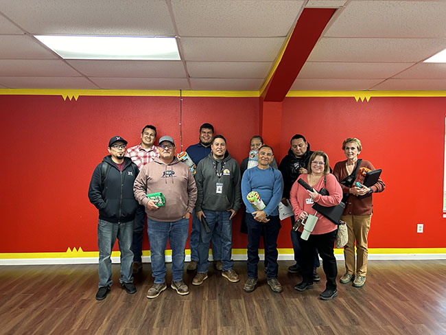Training attendees standing in front of a bright red wall Training attendees standing in front of a bright red wall