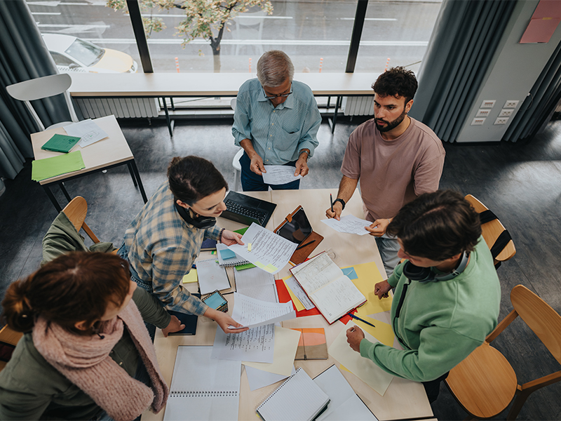 image of a group of 5 people working together around a table