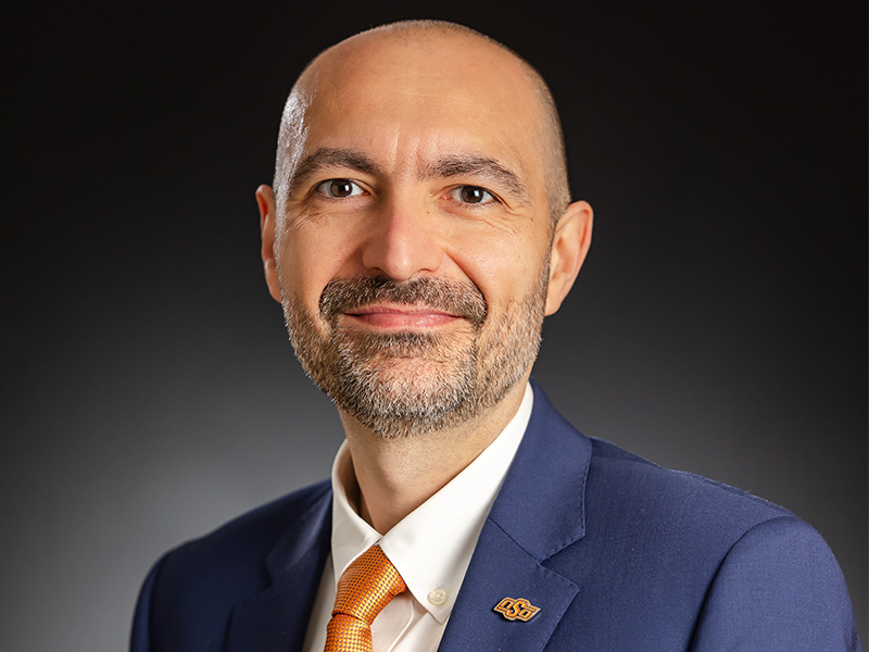 headshot of rasim guldiken standing in front of palm fronds and smiling