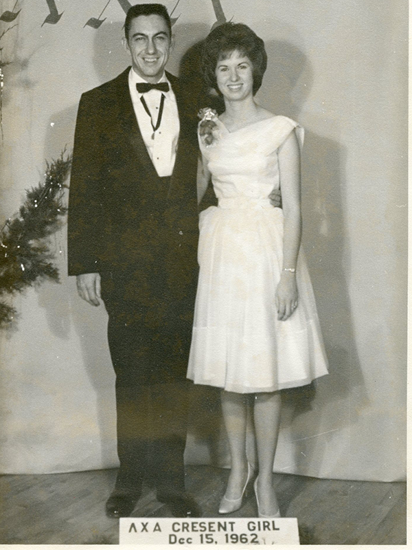A man and a woman posed together in elegant attire.