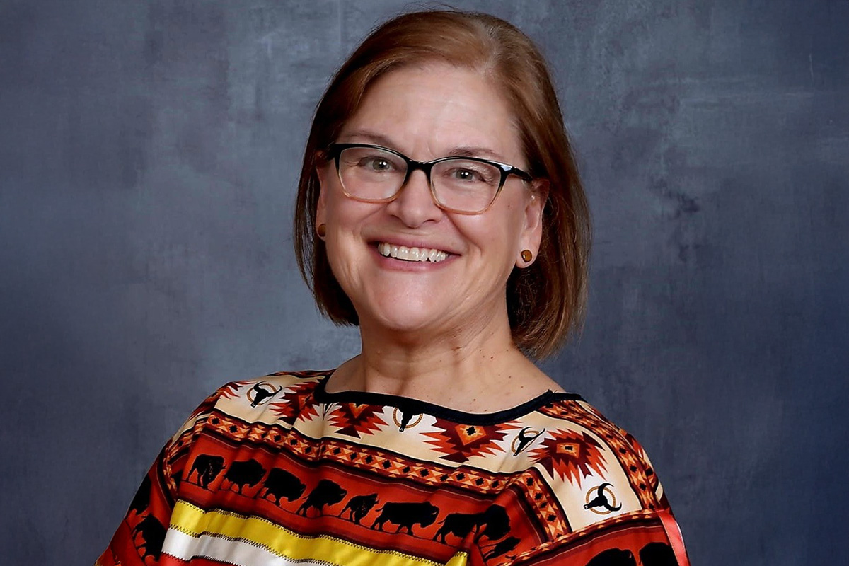 brit_header.jpg A women dressed in a Native American print shirt sits in a portrait pose smiling.