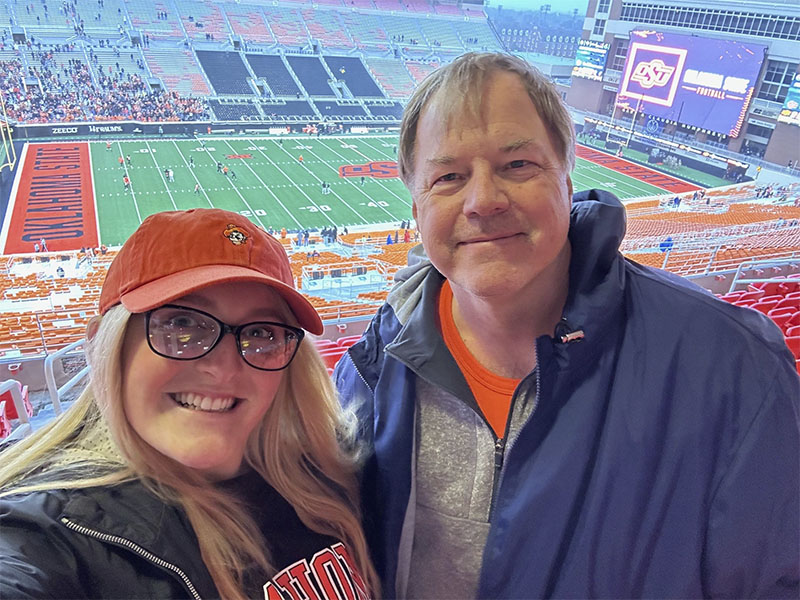 A father and daughter stand inside indoor seating at Boone Pickens Stadium 