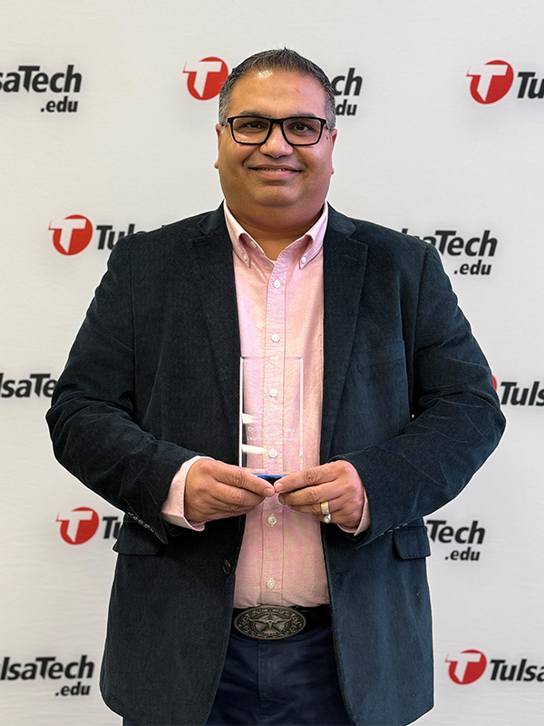 Dr. Hitesh Vora is pictured in a portrait style photo holding an award he received. 