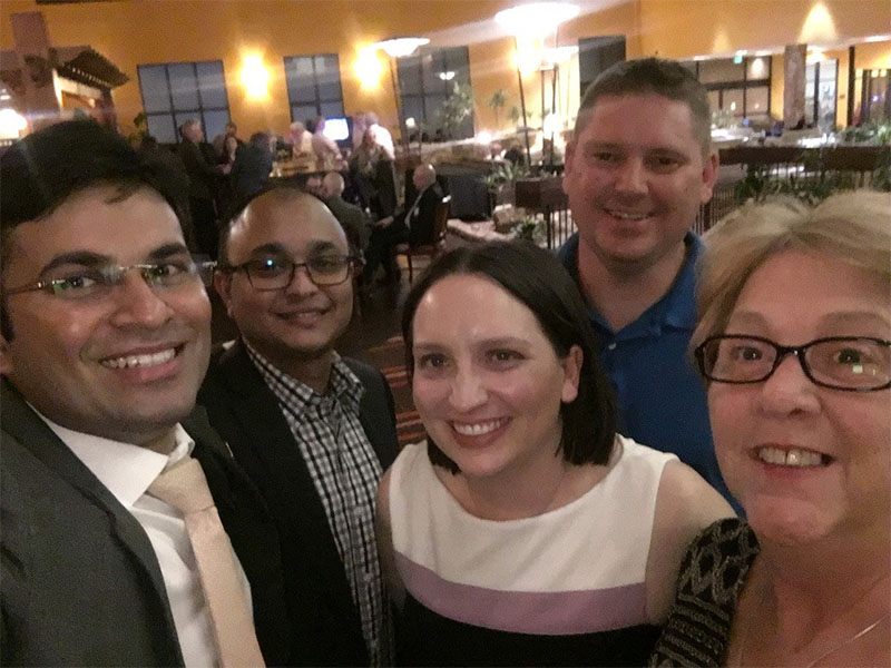 A group of happy individuals take a selfie at a casual business environment.