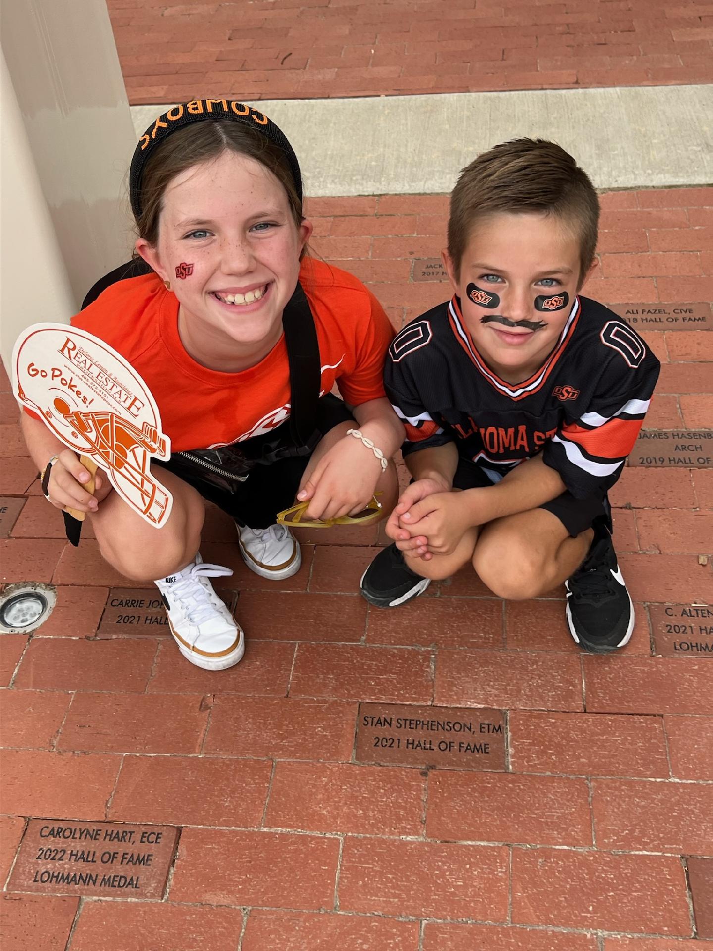 Two children dressed in OSU standing next to a brick that states Stan Stephenson Hall of Fame Two children dressed in OSU standing next to a brick that states Stan Stephenson Hall of Fame