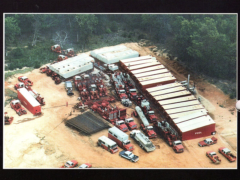 An aerial shot that shows several red trucks congregated on industrial land.