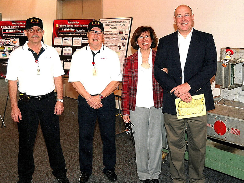 A group photo where a individual is receiving an award. 
