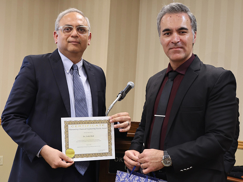 A man smiles after receiving an engineering faculty award. 
