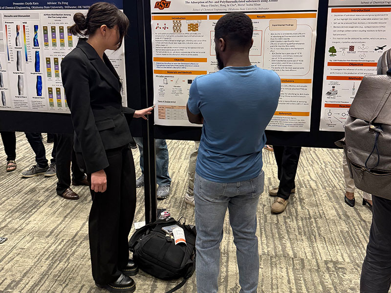An undergraduate chemical engineering student with their research poster.