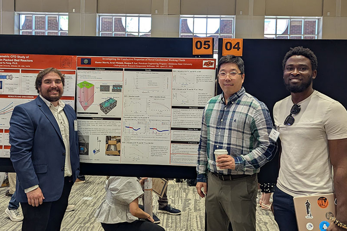 An undergraduate student, advisor, and a master's student stand infront of a research poster.