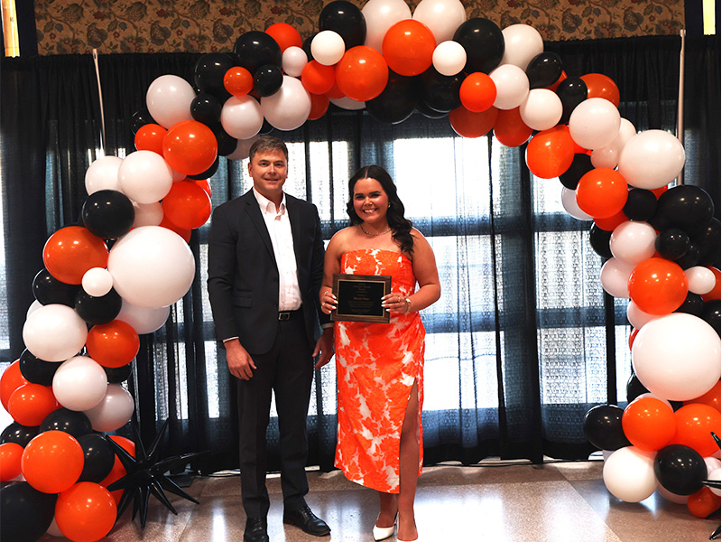 A woman stands smiling after receiving an award. 