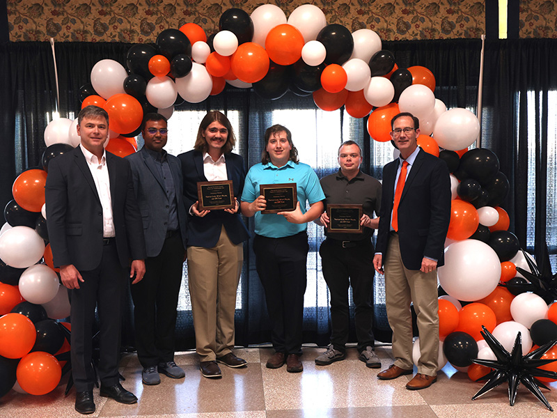 A group of students stands smiling after receiving an award. 
