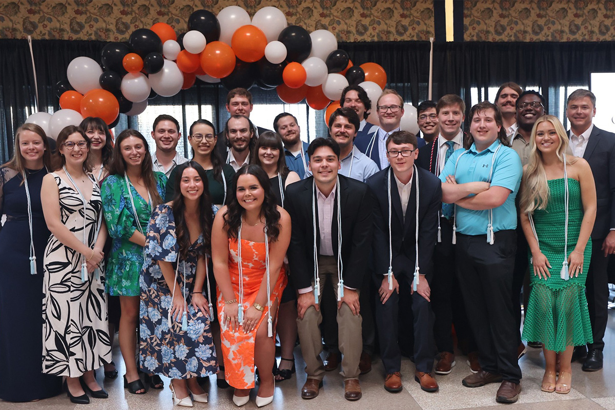 Several well-dressed people pose for a group photo following a banquet.