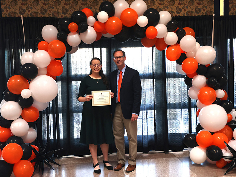 A woman stands smiling after winning an award.