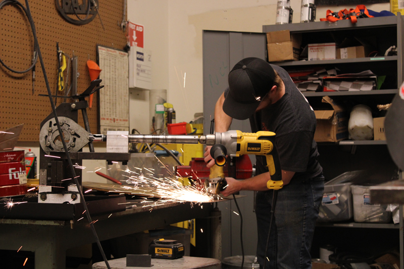 Baja student grinding on metal sheet to create a suspension jig